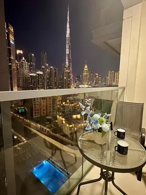 a glass table on a balcony with a view of a city at FULL Burj Khalifa View Luxury Stay in Downtown in Dubai