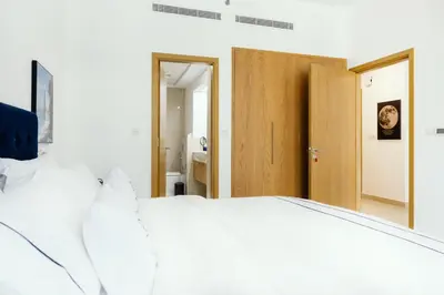 a bedroom with a white bed and a wooden door at FULL Burj Khalifa View Luxury Stay in Downtown in Dubai