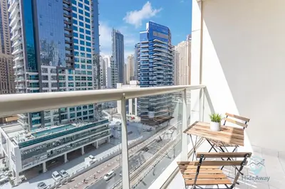 a balcony with a chair and a view of a city at Lovely Cozy Studio l Steps to JBR in Dubai