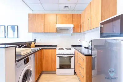 a kitchen with wooden cabinets and a washer and dryer at Lovely Cozy Studio l Steps to JBR in Dubai