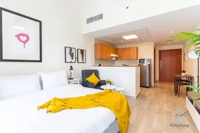 a bedroom with a bed with a yellow blanket on it at Lovely Cozy Studio l Steps to JBR in Dubai