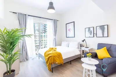 a bedroom with a bed and a blue couch at Lovely Cozy Studio l Steps to JBR in Dubai