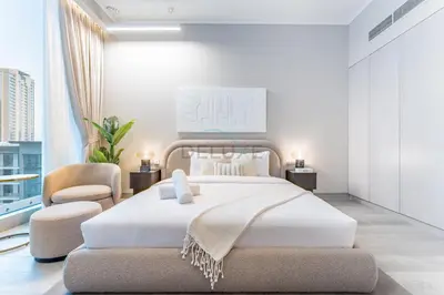 a bedroom with a large white bed and a chair at Pool View Studio with Balcony Close to Mall, Concept 7 Residences, Jumeirah Village Circle by Deluxe Holiday Homes in Dubai