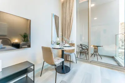 a dining room with a table and chairs and a window at Pool View Studio with Balcony Close to Mall, Concept 7 Residences, Jumeirah Village Circle by Deluxe Holiday Homes in Dubai