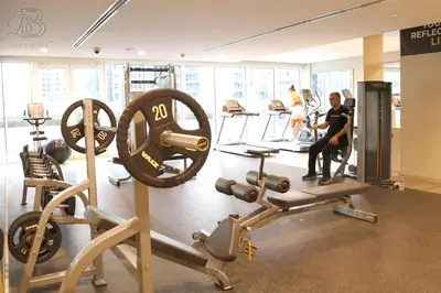 a gym with weights and people in the background at Stylish 2BR Apt in Business Bay Burj & Creek Views in Dubai