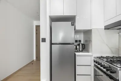 a white kitchen with a refrigerator and a stove at Modern 1BR Apartment - JVC - WiFi - Pool - Gym in Dubai
