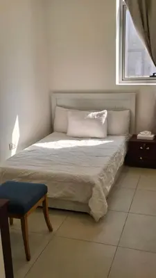 a bedroom with a bed with a chair and a window at Amiqa Homes DIP 1 in Dubai