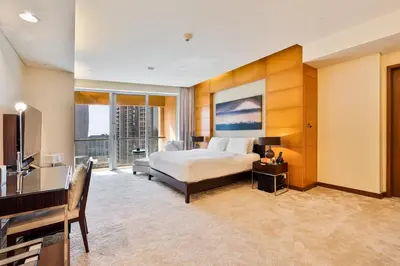 a bedroom with a bed and a desk and a television at Luxurious Studio with Burj Khalifa View Direct Dubai Mall Access - Kempinski Residence in Dubai