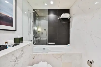 a white bathroom with a tub and a sink at Luxurious Studio with Burj Khalifa View Direct Dubai Mall Access - Kempinski Residence in Dubai