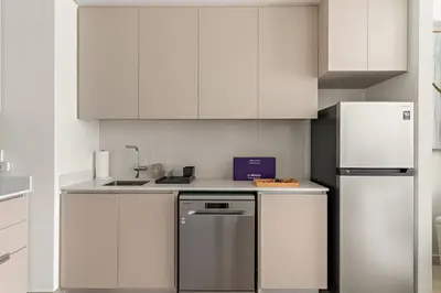 a kitchen with white cabinets and a refrigerator at Silkhaus Chic 1BR in Creek Beach Grove with Pool view in Dubai