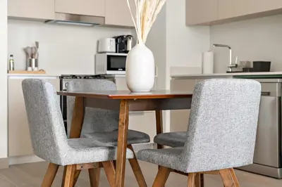 a dining room table with two chairs and a vase on it at Silkhaus Chic 1BR in Creek Beach Grove with Pool view in Dubai