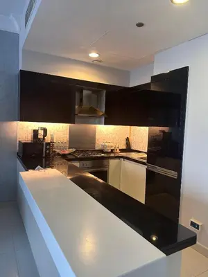 a kitchen with black cabinets and a white counter top at Cozy 1BR, 2Min to Dubai Mall in Dubai