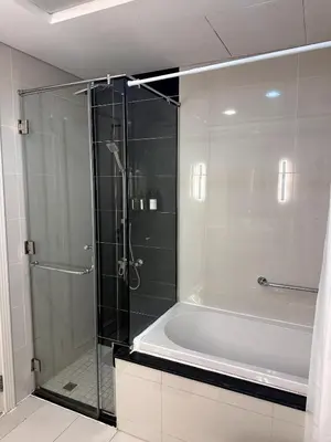 a glass shower in a bathroom with a tub at Cozy 1BR, 2Min to Dubai Mall in Dubai