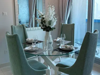 a dining room table with chairs and a vase of flowers at Stylish 1BR, 2Min to Dubai Mall in Dubai