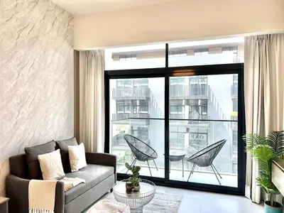 a living room with a couch and a large window at Stylish Stay in the Heart of JVC in Dubai