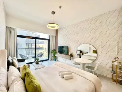 a bedroom with a large bed and a living room at Stylish Stay in the Heart of JVC in Dubai