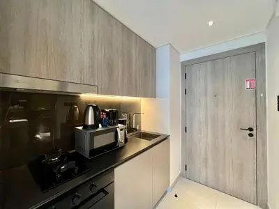 a small kitchen with a microwave and a door at Stylish Stay in the Heart of JVC in Dubai