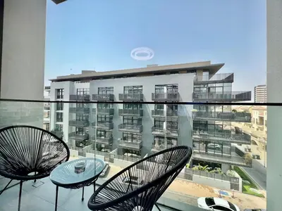a balcony with two chairs and a table and a building at Stylish Stay in the Heart of JVC in Dubai