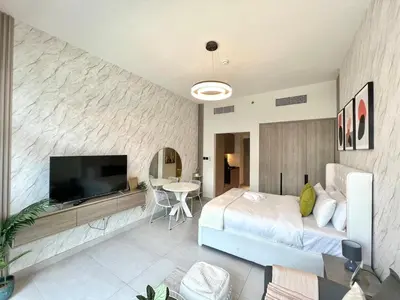 a bedroom with a bed and a flat screen tv at Stylish Stay in the Heart of JVC in Dubai