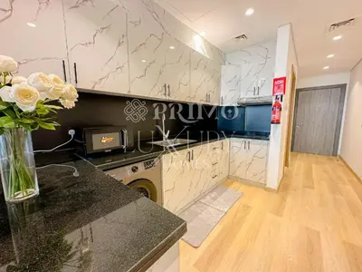 a kitchen with a vase of flowers on a counter at Comfy 1-Bedroom Apartment at Blue Wave - Liwan in Dubai