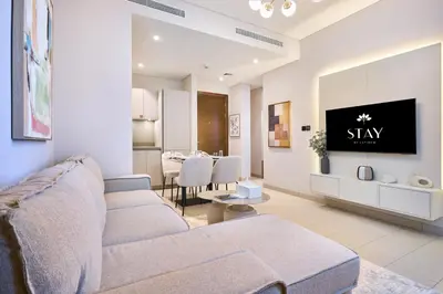 a living room with a couch and a tv on a wall at STAY BY LATINEM Luxury 1BR Holiday Home CVR A901 near Downtown in Dubai