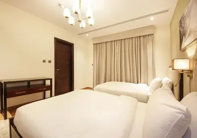 a white bedroom with two beds and a chandelier at Stylish 2BR Downtown Apartment Burj & Mall Nearby in Dubai