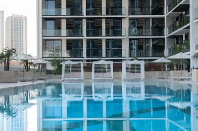 a swimming pool with chairs and a building at Peaceful 1br Jvc Pool, Balcony, Parking in Dubai