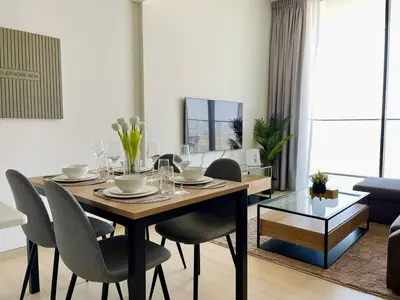 a dining table and chairs in a living room at Jvc 1br Apartment Modern Comfort, Pool, Parking in Dubai