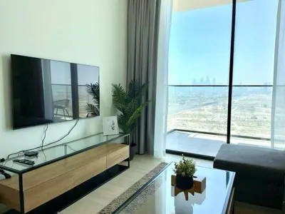 a living room with a large television and a large window at Jvc 1br Apartment Modern Comfort, Pool, Parking in Dubai