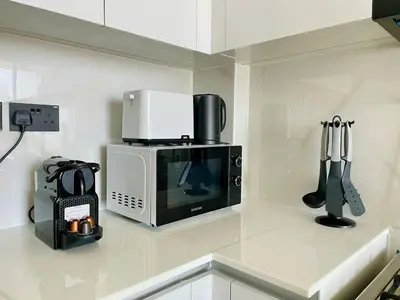 a kitchen counter with a microwave and utensils at Jvc 1br Apartment Modern Comfort, Pool, Parking in Dubai