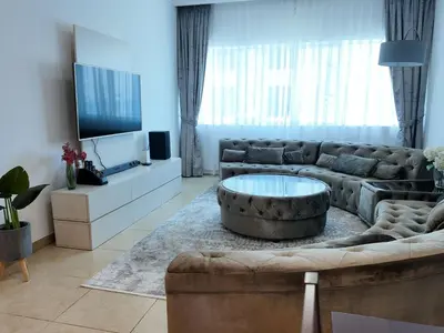 a living room with a large couch and a tv at Spacious 1 Bedroom Plus Hall in Mag218 in Dubai