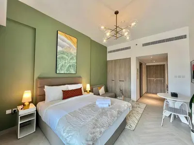 a bedroom with a large bed with a green wall at Prime Studio in the Heart of JVC-Dubai in Dubai
