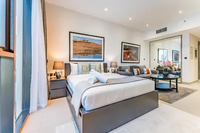 a bedroom with a large bed and a living room at Near Circle Mall and steps from the park, Hyati Avenue, JVC by Deluxe Holiday Homes in Dubai