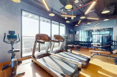 a gym with cardio machines and a treadmill at Near Circle Mall and steps from the park, Hyati Avenue, JVC by Deluxe Holiday Homes in Dubai
