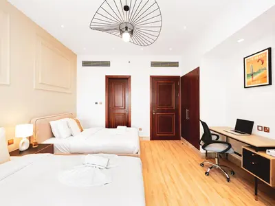 a bedroom with two beds and a desk with a computer at New Fairmont Residence with private beach on PalmJumeirah in Dubai