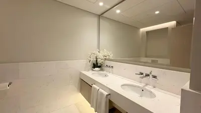 a white bathroom with a sink and a mirror at St. Regis Sky Residence at Palm Tower by DRP Holiday Homes in Dubai