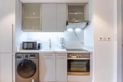 a kitchen with white cabinets and a washing machine at Vacationer I Luxe Studio I Steps to Burj Khalifa & Dubai Mall I Free Parking, Pool, Gym & Wi-Fi in Dubai