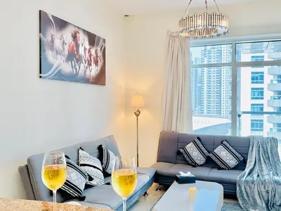 a living room with a couch and two wine glasses at Stylish 1BHK in Marina Steps to Metro & Marina Walk in Dubai