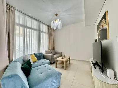 a living room with a blue couch and a television at 3 BR Fully Furnished with BBQ Griller in Dubai