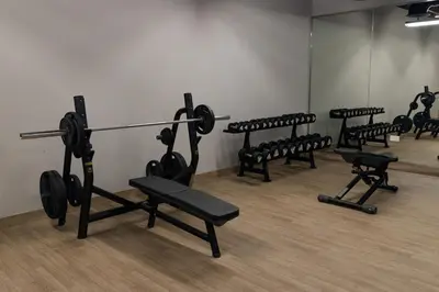 a gym with a row of benches with weights at Chic 2BR in Oakley Square Residence, JVC in Dubai