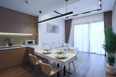 a kitchen and living room with a white table and chairs at Chic 2BR in Oakley Square Residence, JVC in Dubai