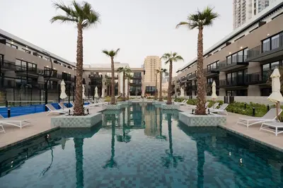 a swimming pool with palm trees in a building at Luxurious 2BR in Oakley Square Residence, JVC in Dubai