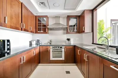 a large kitchen with wooden cabinets and a sink at Silkhaus near Burj Khalifa in 1BDR in 29 BLVD in Dubai
