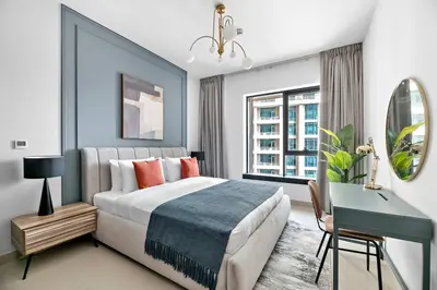 a bedroom with a bed and a desk and a window at Silkhaus near Burj Khalifa in 1BDR in 29 BLVD in Dubai