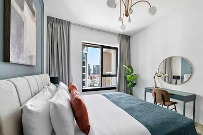 a bedroom with a bed and a desk and a window at Silkhaus near Burj Khalifa in 1BDR in 29 BLVD in Dubai