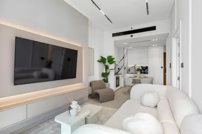 a living room with a white couch and a tv at Exclusive 1 Bedroom in Trillionaire Residences in Dubai