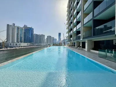 a large blue swimming pool next to a building at Exclusive 1 Bedroom in Trillionaire Residences in Dubai