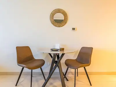 a table with two chairs and a mirror on a wall at Stylish Studio Escape in the Heart of JLT in Dubai