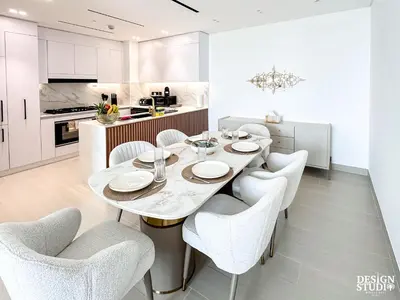 a white kitchen with a dining table and chairs at GOLDEN NUMBER by Design Studio in Dubai