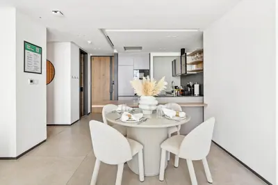 a white dining room with a white table and chairs at Large 2BR with Work Desk, Pool, Gym and Kids Area in Dubai